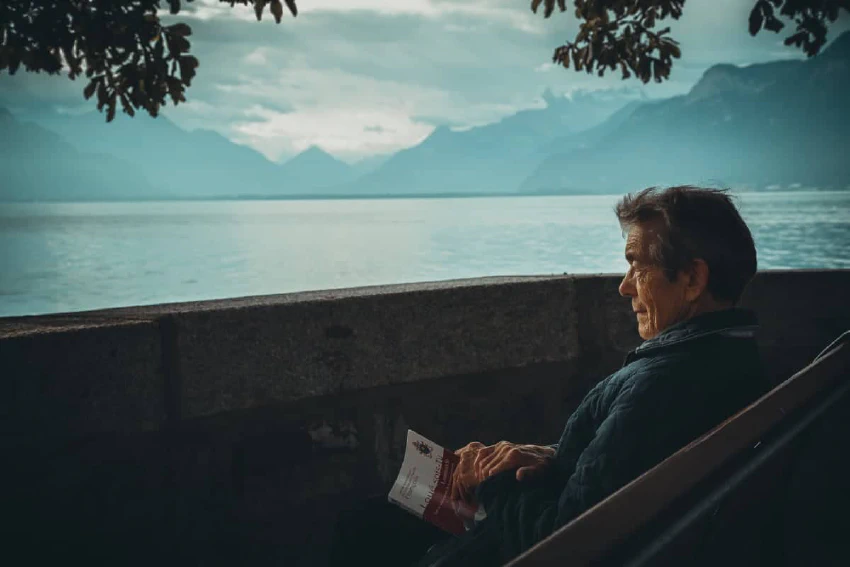 Person sitting on a bench looking at a lake