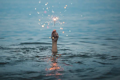 Hand sticking out of the water and holding a sparkler