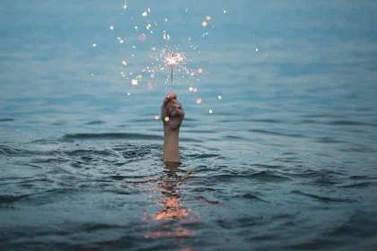 Hand sticking out of the water and holding a sparkler