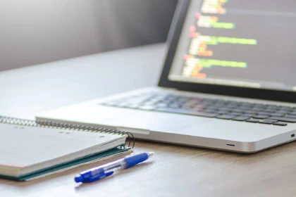 Laptop with code, notebook, and pen